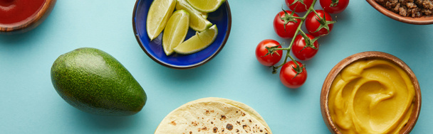 Top view of tortillas with fresh ingredients for taco on blue background, panoramic shot - 写真・画像