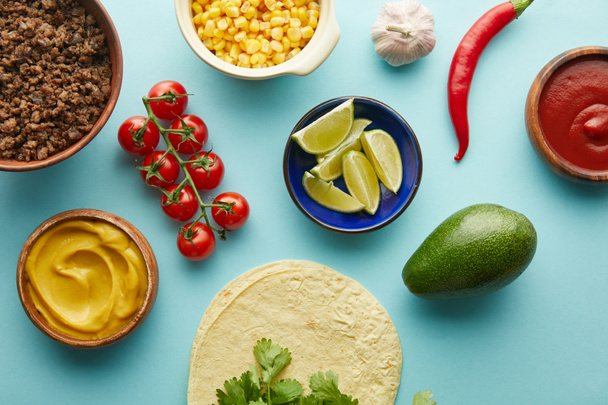 Fresh tortillas with taco ingredients, mustard and tomato sauce on blue background - Foto, imagen