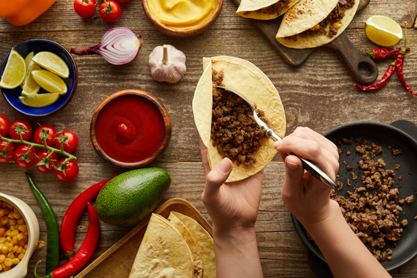 Taco 'ya doğranmış et ve ahşap yüzeyde ham malzeme eklenen insan görüntüsü. - Fotoğraf, Görsel