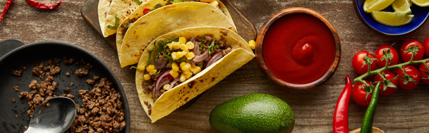 Top view of traditional mexican tacos with ketchup and ingredients on wooden surface, panoramic shot - Fotó, kép