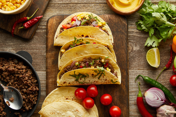 Top view of traditional mexican tacos with organic ingredients on wooden background - Fotó, kép
