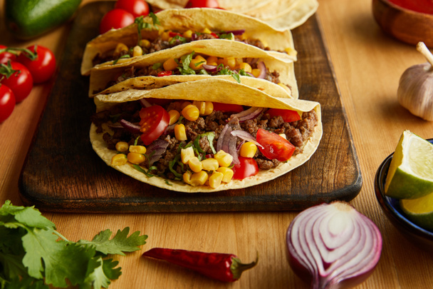Traditional mexican tacos with ripe vegetables on wooden table - Photo, Image