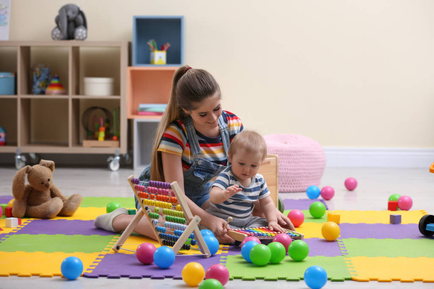 Teen nanny and cute little baby playing with xylophone at home - Photo, Image