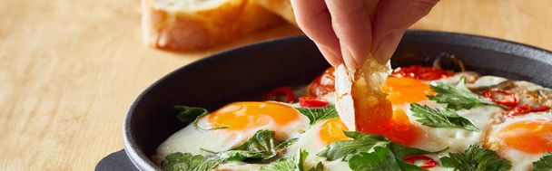cropped view of eating fried eggs with bread at wooden table, panoramic shot - Foto, Imagem