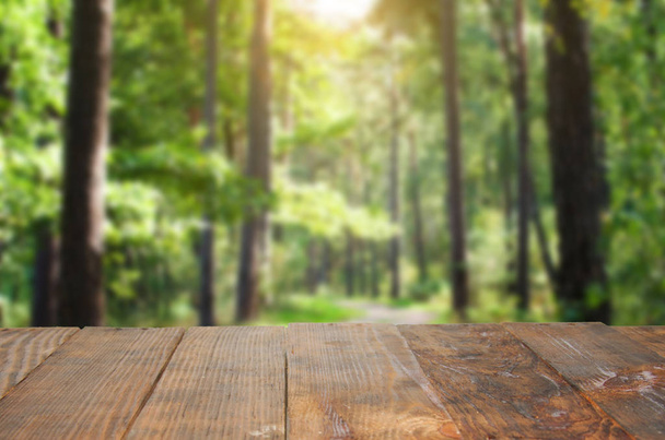 Empty old Dark wooden rustic table top made of planks with uneven edges on blurred Forest path in the summer forest, Blooming greenery. Background, used for display or montage your products. - Φωτογραφία, εικόνα