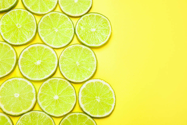 Juicy fresh lime slices on yellow background, flat lay. Space for text - Foto, Bild