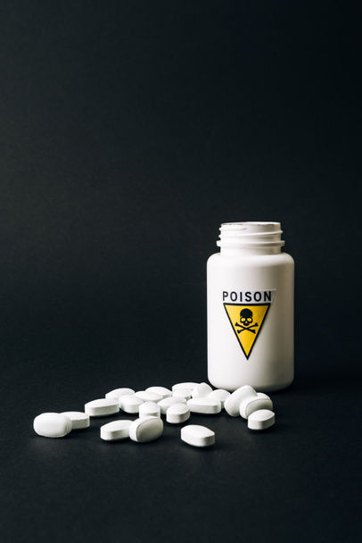 Bottle with poison sign and pills isolated on black - Valokuva, kuva