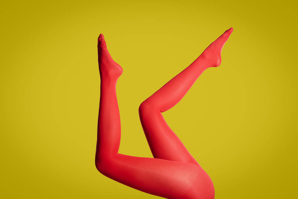 Woman wearing red tights on yellow background, closeup of legs - Fotó, kép
