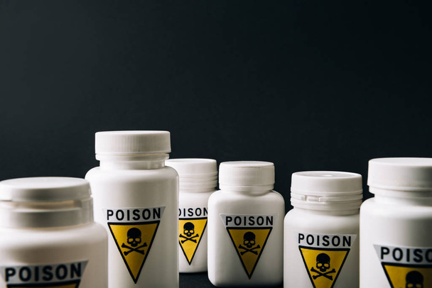 Bottles with poison symbol isolated on black - 写真・画像