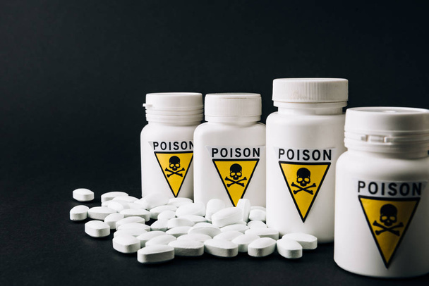 Bottles with poison sign and pills isolated on black - Φωτογραφία, εικόνα