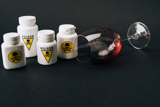 Weinglas mit Blut und Gläser mit Giftzeichen isoliert auf schwarz - Foto, Bild