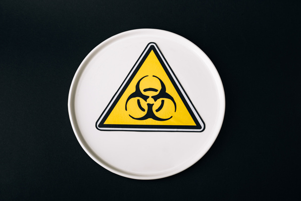 Platte von oben mit Biohazard-Zeichen isoliert auf schwarz - Foto, Bild