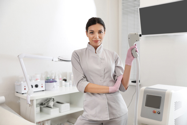 Młoda kobieta trzyma profesjonalny depilator laserowy w salonie piękności - Zdjęcie, obraz
