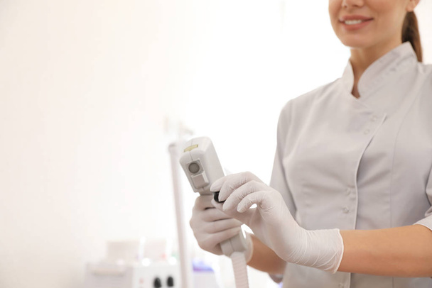 Young woman holding professional laser epilator in beauty salon, - Foto, afbeelding