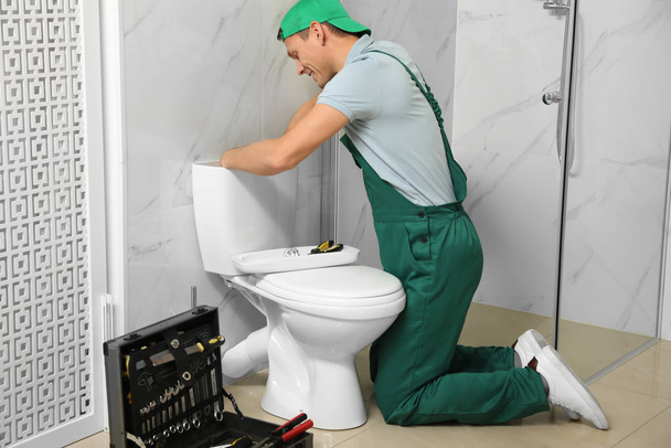 Professional plumber repairing toilet tank in bathroom - Foto, Imagen