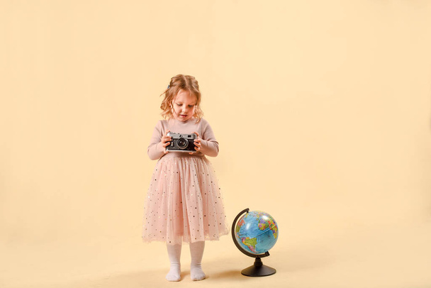 Smiling cute schoolgirl. laughing baby girl with a globe in the studio on a pink background. The concept of studying at school, or travel - Foto, Imagen