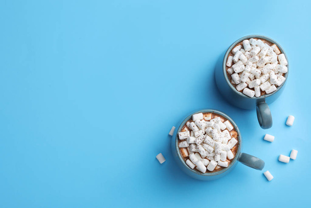 Delicious cocoa drink with marshmallows on light blue background, flat lay. Space for text - Valokuva, kuva