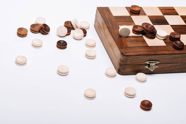 Дерев'яна шашка і шахова дошка ізольовані на білому
 - Фото, зображення