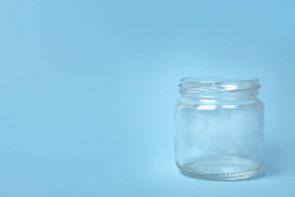 Open empty glass jar on light blue background, space for text - Fotó, kép