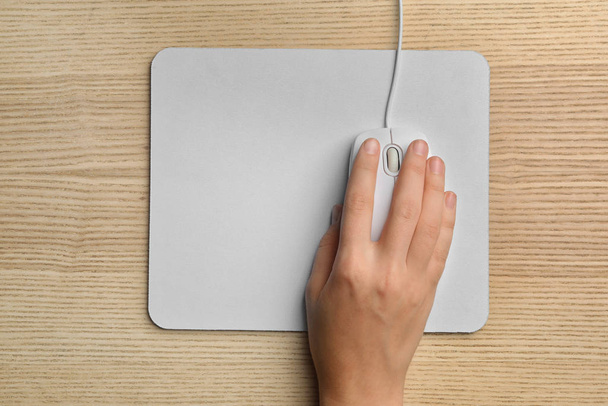 Woman using wired computer mouse on wooden table, top view. Space for text - Foto, imagen