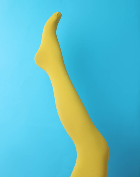 Leg mannequin in yellow tights on blue background - Φωτογραφία, εικόνα