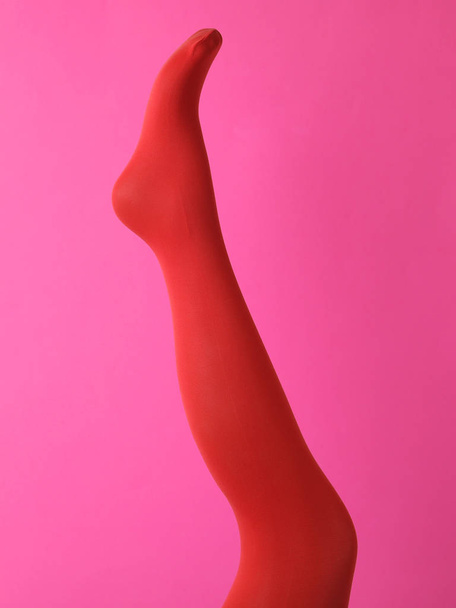 Leg mannequin in red tights on pink background - Foto, afbeelding