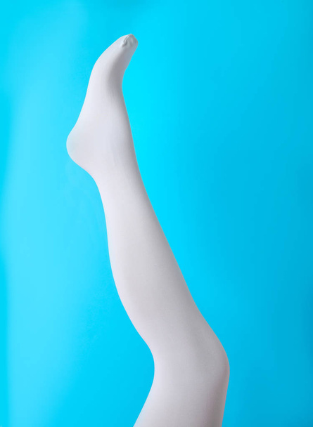 Leg mannequin in white tights on blue background - Foto, Imagen