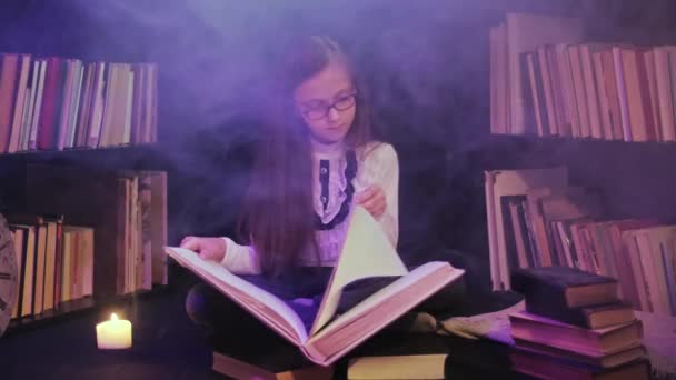 Egy lány nyit egy mesekönyvet a könyvtárban, színes füst kavarog körülötte, gyertyákat gyújtanak a közelben. - Felvétel, videó