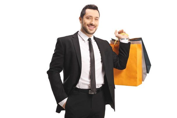Elegant young man smiling and carrying shopping bags  - Фото, зображення