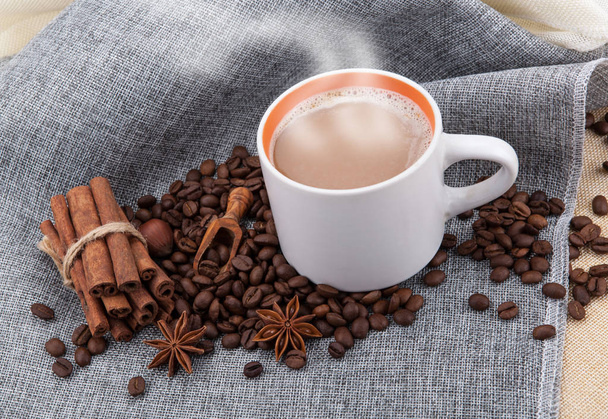 Tasse Milchkaffee auf farbigem Tuch und gerösteten Kaffeebohnen clo - Foto, Bild