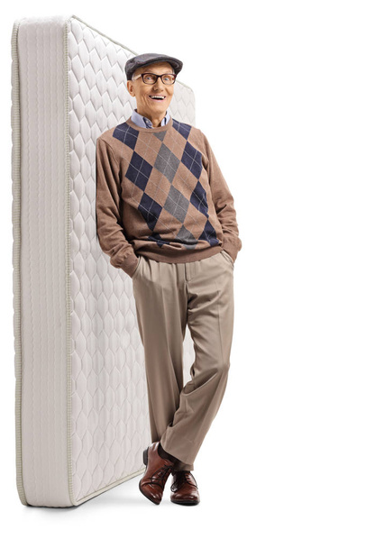 Older gentleman standing and leaning on a mattress - Фото, изображение