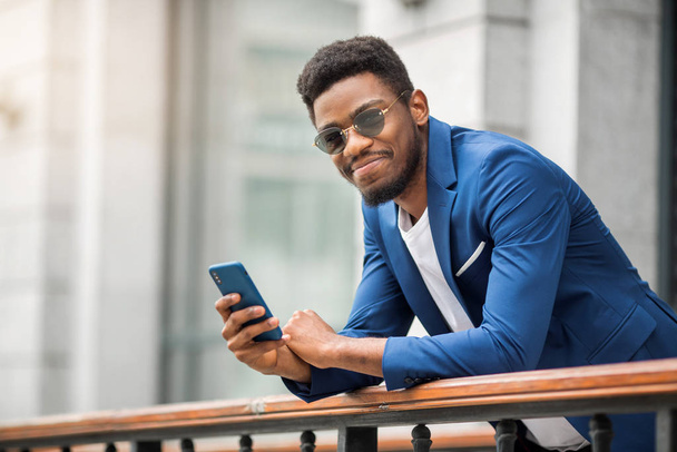 handsome african man in a blue jacket with a phone in his hand - Foto, Imagen