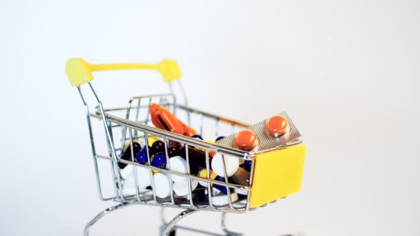 Supermarket trolley filled with medical capsules on a white background - Záběry, video