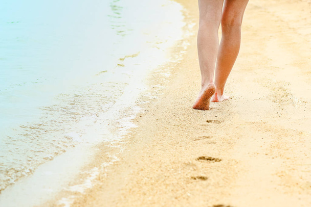 gyönyörű lábnyomok a homokban a tenger háttere mellett - Fotó, kép