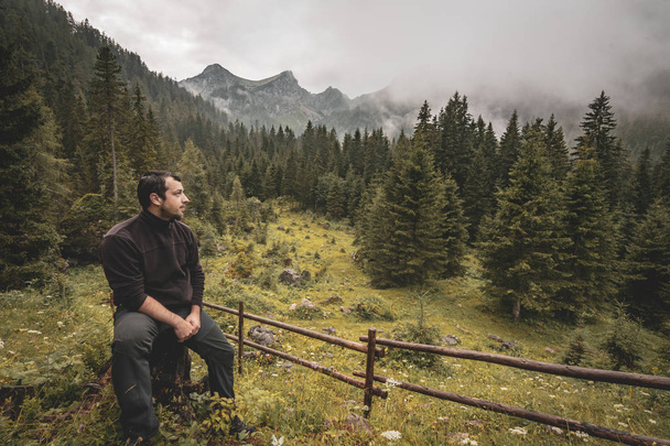 Un homme solitaire devant un paysage montagneux isolé par un jour de pluie
 - Photo, image