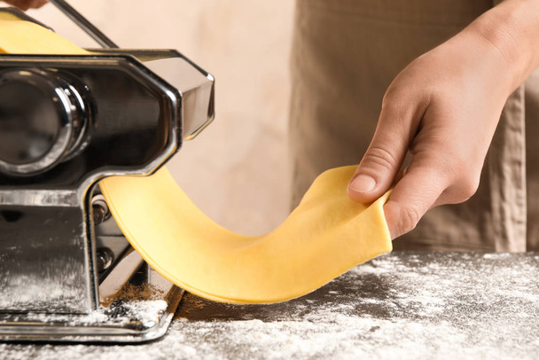 Woman preparing dough with pasta maker machine at table, closeup - Foto, immagini