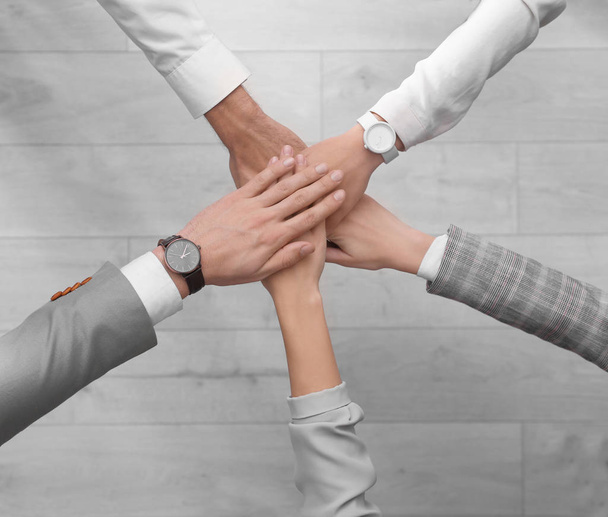 People holding hands together over light wooden background, top view. Unity concept - Fotografie, Obrázek