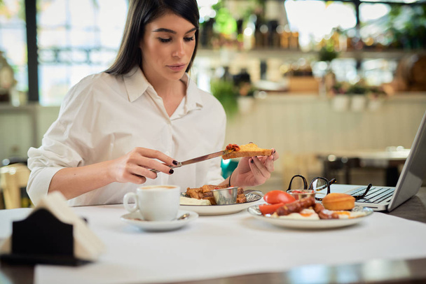 Krásná žena jíst francouzský toust k snídani, zatímco sedí v restauraci. - Fotografie, Obrázek
