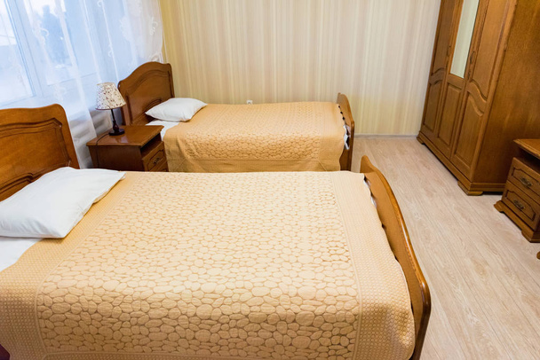 Interno della moderna camera d'albergo economica con due letti singoli in colore beige
 - Foto, immagini