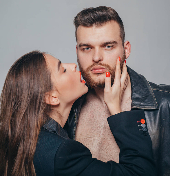 Touch his bristle. Girlfriend passionate red lips and man leather jacket. She adores male beard. Passionate hug. Passionate couple in love. Man brutal well groomed macho and attractive girl cuddling - Photo, Image