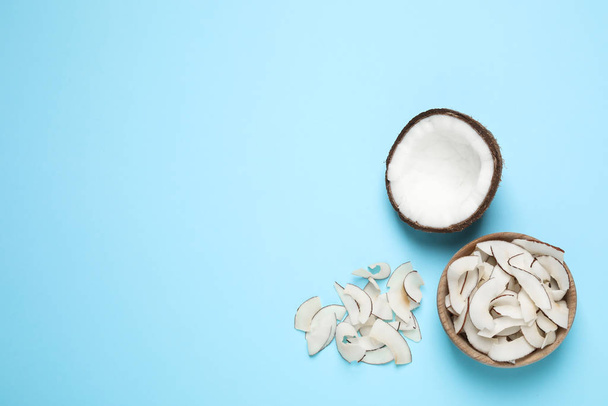 Flat lay composition with tasty coconut chips on light blue background. Space for text - Foto, Imagen