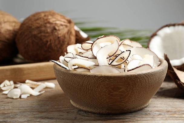 Tasty coconut chips in bowl on wooden table - Fotografie, Obrázek