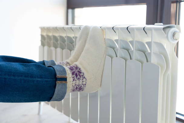 Vrouwelijke voeten op verwarming met wollen sokken - Foto, afbeelding