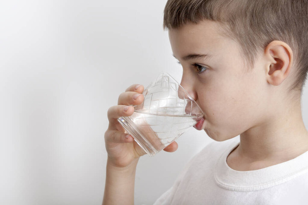 Chłopak pije wodę ze szklanki. Koncepcja czystej wody - Zdjęcie, obraz