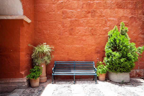 There is a bench near the red wall Saint Catalina, Arequipa, Peru - Photo, Image