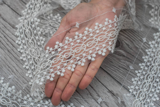perlas de coser a mano a la tela de seda de encaje blanco, hacer un vestido de novia, decorar con bordado
 - Foto, imagen