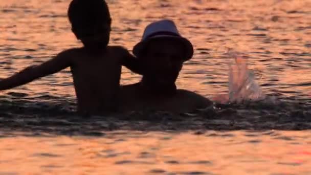 Parent and son in the sea with sunset reflecting in the water. Family tours, trips. Travel to Europe. Summer vacation background. Travel trend concept. Original travel. Unique places, locations - Footage, Video