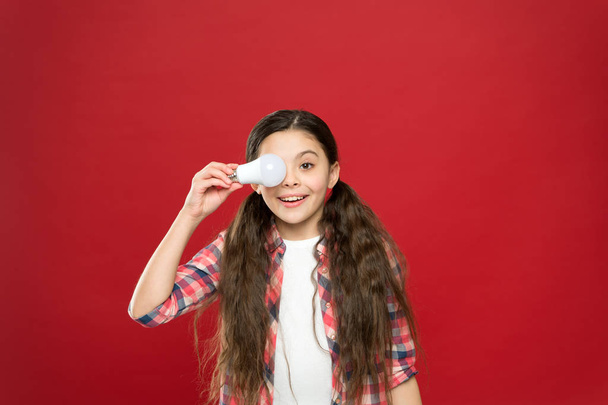 girl of success. cheerful child girl. little child hold light idea bulb. education concept. small school kid red background. small girl lightbulb. energy and electricity. creating a great idea - Foto, imagen