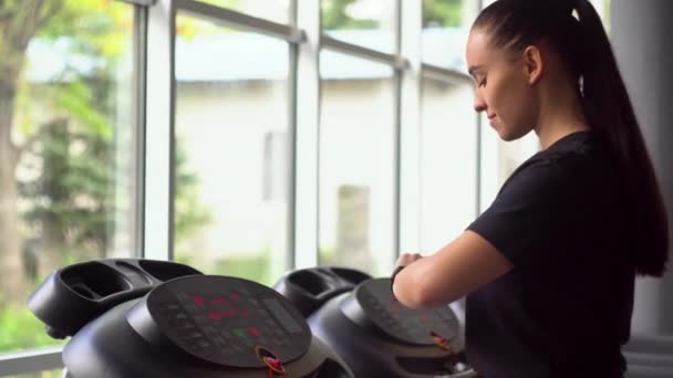 Atrakcyjna dziewczyna biegająca na bieżni w siłowni - Materiał filmowy, wideo