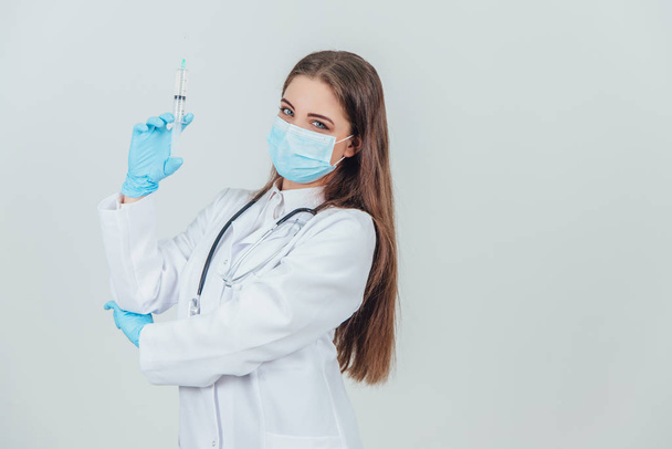 Smiling confident female doctor in medical mask holding syringe. - Fotó, kép